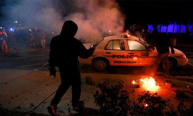 Demonstranten setzen ein Polizeiauto in Brand.