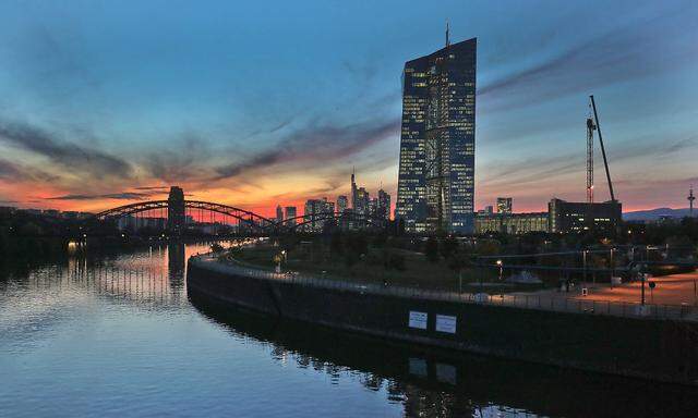 Die Zentrale der Europäischen Zentralbank EZB im Abendlicht, im Hintergrund die Frankfurter Skyline