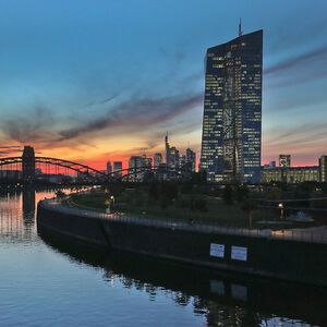 Die Zentrale der Europäischen Zentralbank EZB im Abendlicht, im Hintergrund die Frankfurter Skyline