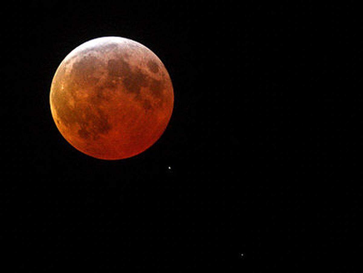 Durch Streulicht, das hauptsächlich von der Erdatmosphäre verursacht wird, bekommt der Mond ein dunkles, kupferrotes Aussehen.Während der totalen Mondfinsternis: Ein Schatten fällt auf den Mond. Gesehen südlich von Skopje.