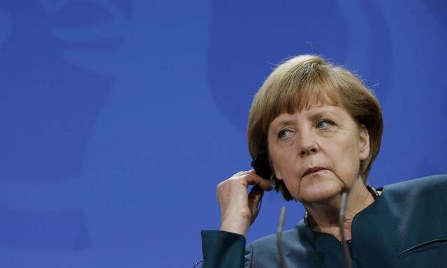 German Chancellor Angela Merkel adjusts her earphone as she addresses  a news conference with Qatari Prime Minister Sheikh Hamad bin Jassim al-Than at the Chancellery in Berlin