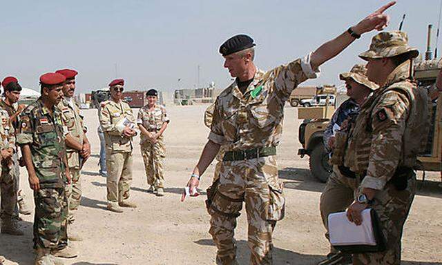 A British soldier, right, talks to Iraqi army soldiers during a training course in Basra airport, Ira