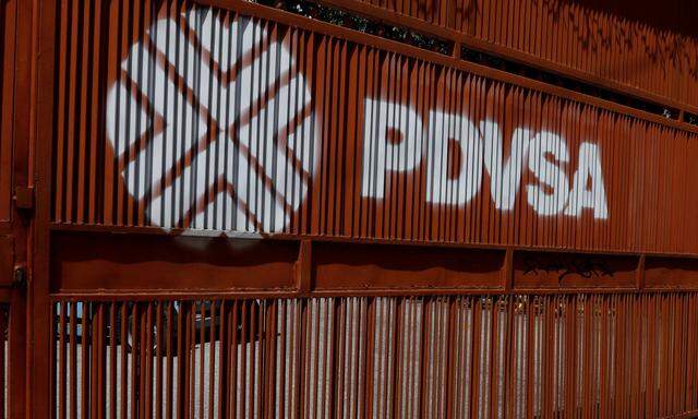 A man walks past a gate with the corporate logo of the state oil company PDVSA in Caracas