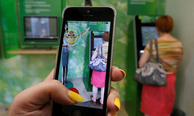 Woman plays augmented reality mobile game 'Pokemon Go' by Nintendo at branch of Sberbank in central Krasnoyarsk