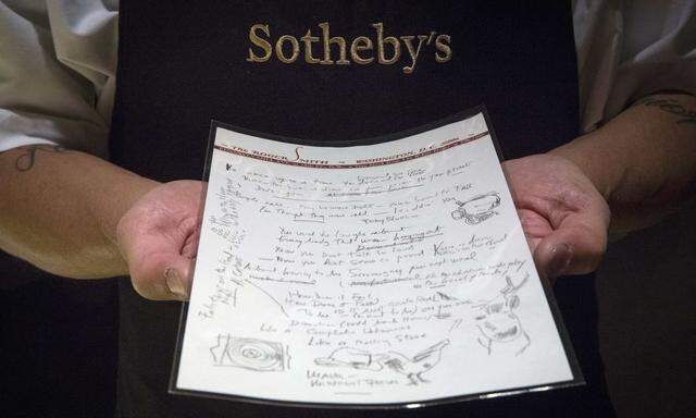 An employee shows the handwritten lyrics for Bob Dylan's 'Like a Rolling Stone' song at Sotheby's in New York