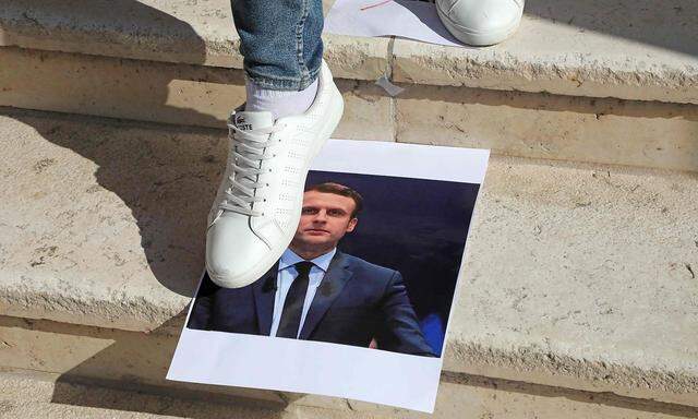 Eine junger Mann steigt bei einer Demonstration an der palästinischen Technischen Universität in al-Aroub auf das Bild des französischen Staatspräsident Emmanuel Macron.
