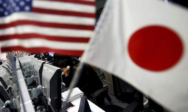 File photo of an employee of a foreign exchange trading company working between the national flags of Japan and the U.S. in Tokyo
