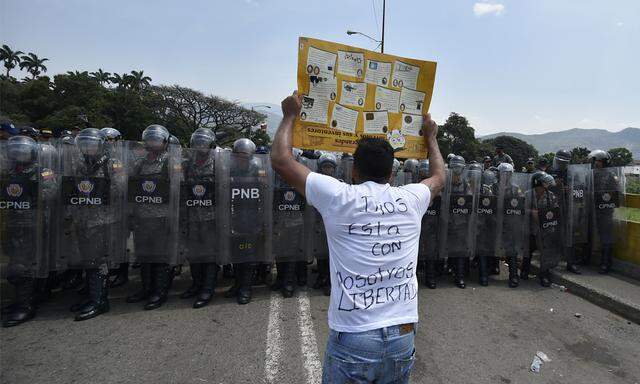 Polizisten stehen einem Anhänger von Oppositionsführer Juan Guaido gegenüber. 