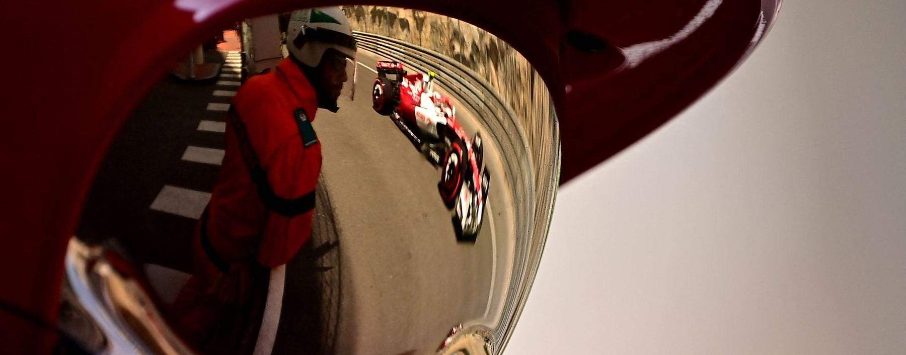 Der Alfa Romeo des chinesischen Fahrers Zhou Guanyu spiegelt sich in Monaco im Visier eines Feuerwehrmannes.