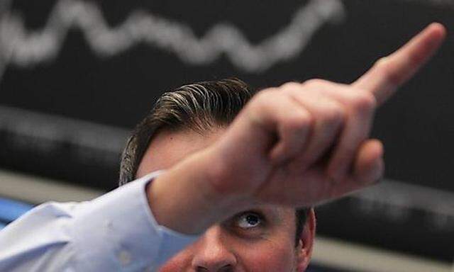Trader gestures at his desk in front of the DAX board at the Frankfurt stock exchange