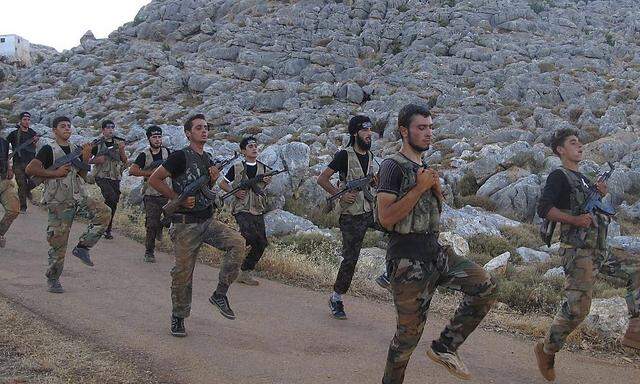 Free Syrian Army fighters, holding their weapons, run during military training north of Idlib