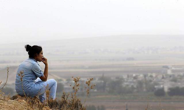 A Turkish Kurd woman watches the Syrian town of Kobani from near the Mursitpinar border crossing