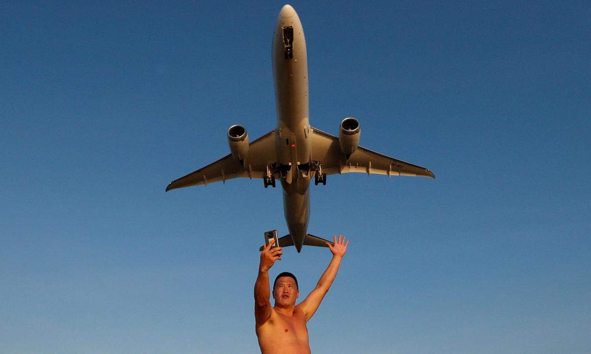 17. Jänner. Ivan, ein Tourist aus Russland, macht ein Selfie am Mai Khao Beach, während ein Flugzeug vom Phuket International Airport in Phuket, Thailand, abhebt.