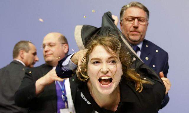 Security officers detain a protester who jumped on the table in front of the European Central Bank President Mario Draghi during a news conference in Frankfurt