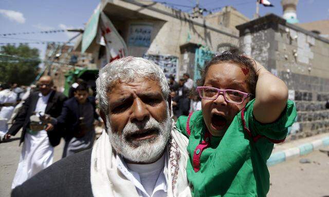 An injured girl reacts as she is carried by a man out of a mosque which was attacked by a suicide bomber in Sanaa