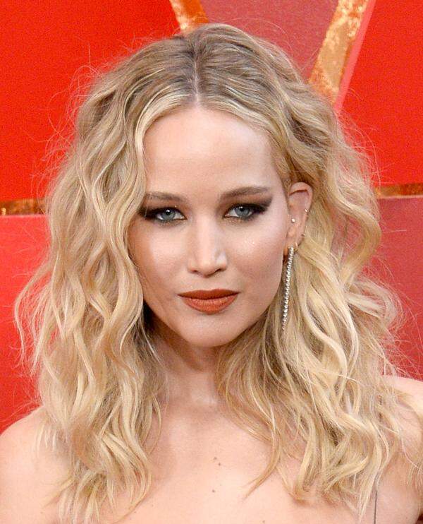 Natürlich gewelltes Haar, geschwungene Smokey Eyes und orangeroter Lippenstift: So konnte Jennifer Lawrence überzeugen.
