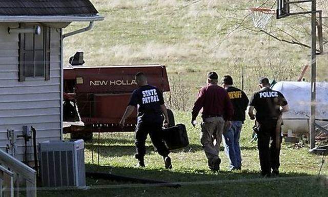 Investigators walk  around a home as they look for evidence on a rural property in western Missouri W