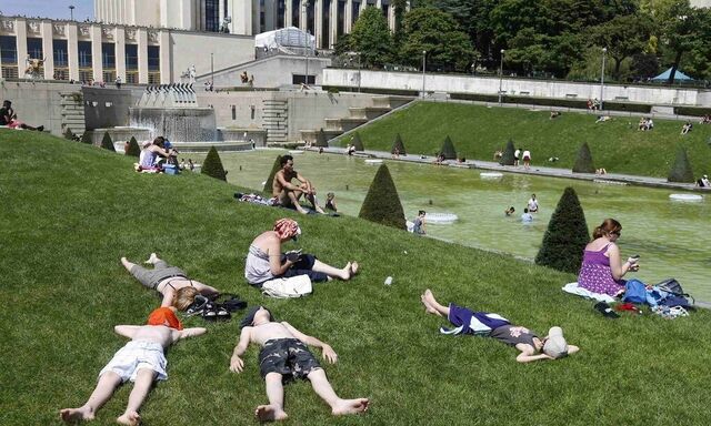 People relax in the sun near the fountains at Trocadero square during a hot summer day in Paris