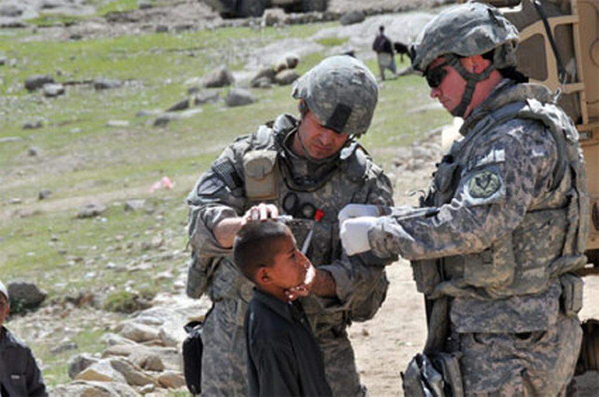 Technical SGT (Sanitäter) Mathew Wiese, Illinois, stationiert in Missisippi, verarztet in Sultankhel (Provinz Kapisa) einen afghanischen Jungen mit einer Kopfverletzung.
