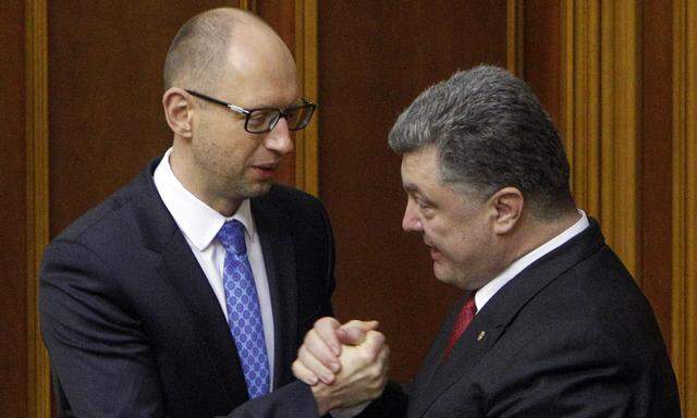 UkraineÂ´s President Poroshenko clasps hands with Prime Minister Yatseniuk after a ratification of a landmark association agreement with the European Union during a parliament session in Kiev