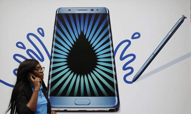 A woman speaks on a phone as she passes an advert for the Samsung Galaxy Note 7 in London