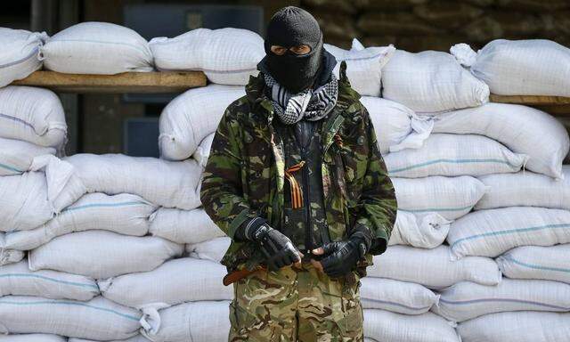 An armed man stands guard in front of barricades outside the mayor's office in Slaviansk