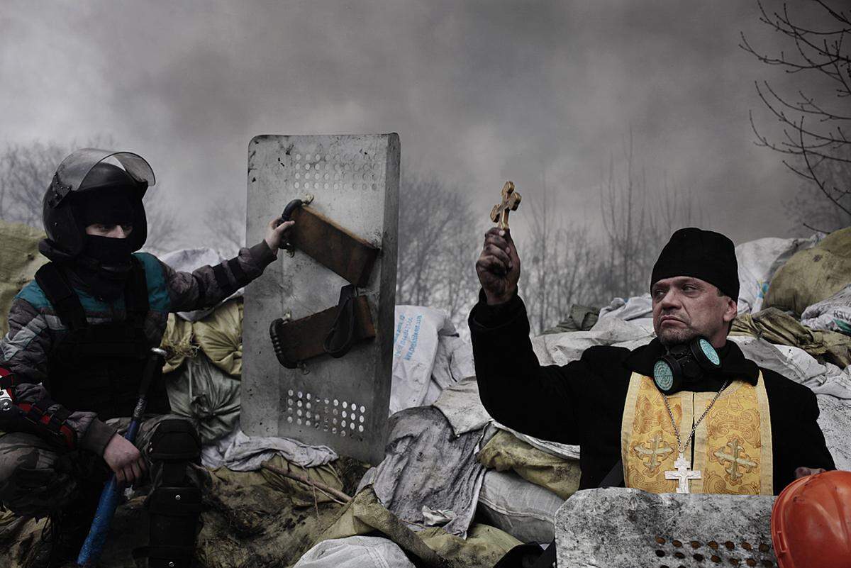 Jérôme Sessini, France, Magnum Photos for TimeEin orthodoxer Priester segnet die Demonstranten vor einer Barrikade in der Ukraine. Am 20. Februar wurden 70 unbewaffnete Personen von nicht identifizierten Scharfschützen getötet.