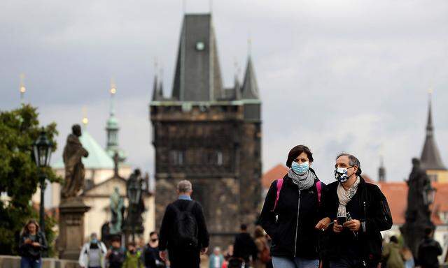 People wearing face masks walk in Prague