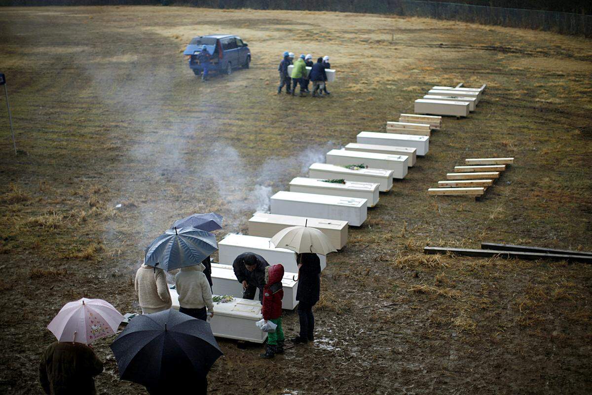 In Kassenuma werden Opfer im Kreis ihrer Familie zu Grabe getragen. 27.000 Menschen gelten vier Wochen nach dem Beben als tot oder vermisst. (26. März)