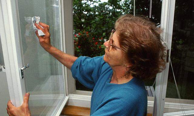 Seniorin putzt ein Fenster