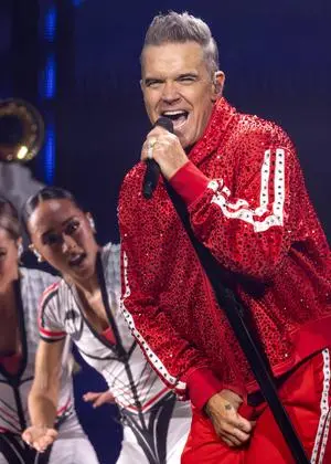 Robbie Williams bei einem Konzert in Manchester im Jahr 2025. Der rote Trainingsanzug sitzt immer noch. 