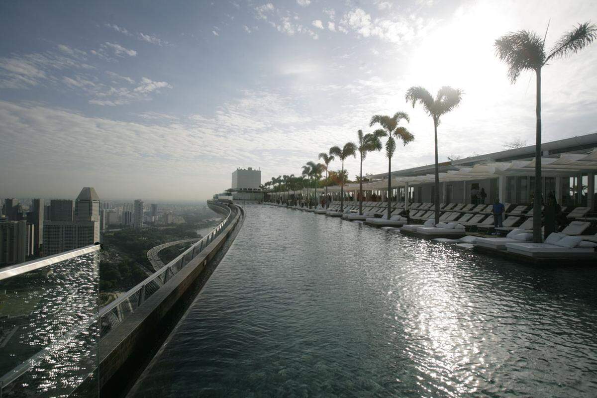 Auf dem Marina Bay Sands in Singapur thront ein gigantisches Planschbecken mit Blick auf die Skyline. Der Panoramapool ist das größte Außenschwimmbad der Welt und mit 146 Metern der längste seiner Art. Der Pool verbindet die drei Türme des Marina Bay wodurch sich in 191 Metern Höhe eine beeindruckende Aussicht auf Singapur bietet.