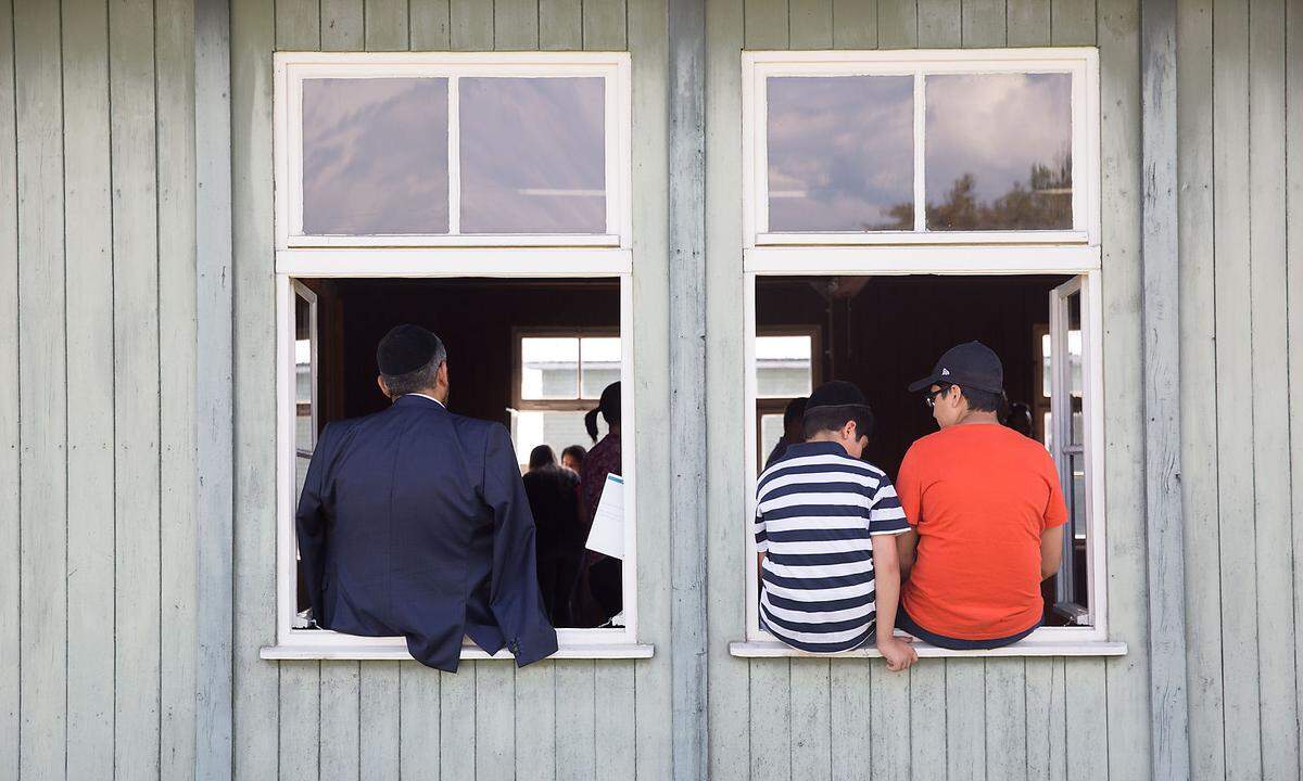 Jüdische Rundgang-Teilnehmer sitzen auf der Fensterbank einer ehemaligen Häftlings-Barracke im KZ Mauthausen.