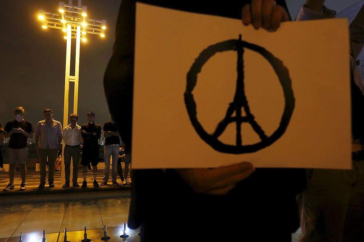 Der Eiffelturm, das Wahrzeichen von Paris, stilisiert zum "Peace"-, zum Friedenssymbol. Der Entwurf ging am Samstag um die Welt. Menschen zeigten damit ihre Verbundenheit mit den Betroffenen in Frankreich - wie hier bei einer Schweigeminute in Hongkong.