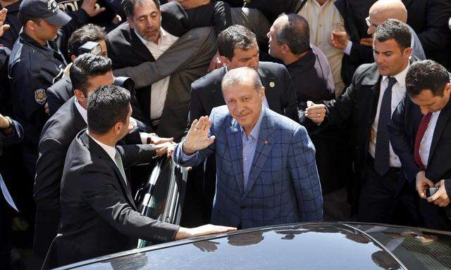 Turkey's Prime Minister Tayyip Erdogan waves hand to supporters during the municipal elections outside a polling station in Istanbul