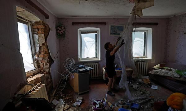 Eine Frau beseitigt die Trümmer des Hauses ihres Freundes in Jasinowataja in der von Russland besetzten Region Donezk, das durch den jüngsten Beschuss beschädigt wurde, den die örtlichen, von Russland eingesetzten Behörden als ukrainischen Militärschlag bezeichneten. 