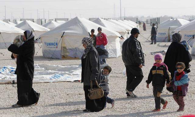 Syrian refugees walk near newly pitched tents at the Al-Zaatari refugee camp in Mafraq