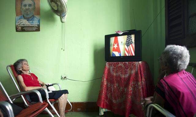 Suarez sits under a picture of former Cuban president Castro to watch U.S. President Obama make a statement about Cuba on television, at the Eterna Juventud retirement home in Havana