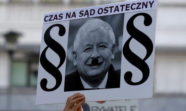 A protester holds a poster with a picture of Law and Justice party leader Jaroslaw Kaczynski and the words 'It is time for the Judgement Day' during an anti-government protest in support of free courts in front of the the Senate building in Warsaw