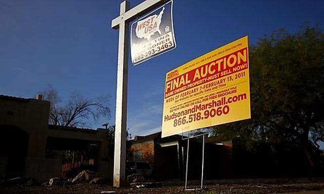 A realtor and bank-owned sign is displayed near a house for sale in Phoenix