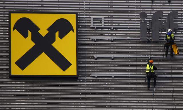 Workers are suspended as they assemble letters of the Raiffeisen Polbank´s bank logo on their new building in Warsaw