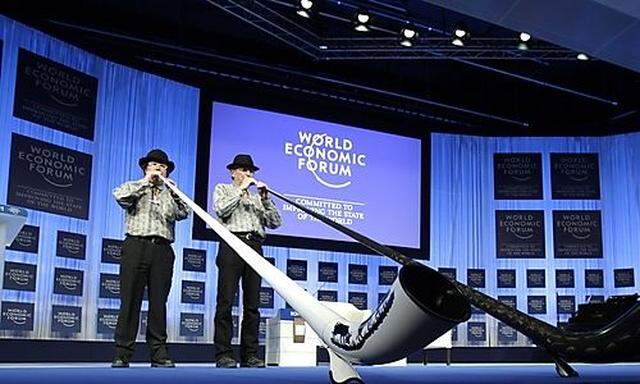 Two men blow traditional Swiss horns prior to the opening address at the World Economic Forum in Davo