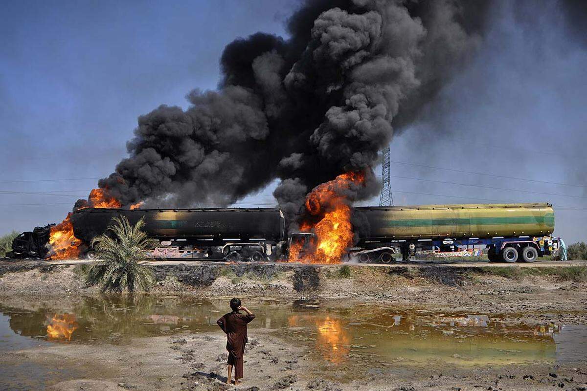 Shikarpur, Pakistan. Ein Bub ist fasziniert von brennenden Tanklastern. Der Convoy ist von unbekannten Bewaffneten angegriffen worden.