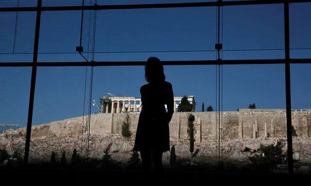 FILE PHOTO: Woman looks at exhibits on display in the Parthenon hall at the Acropolis museum, as the temple of the Parthenon is seen in the background, in Athens