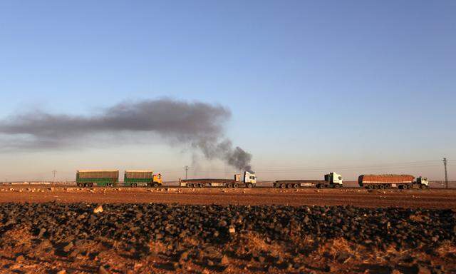 Smoke rises from al-Bab city behind vehicles after shelling, northern Aleppo province