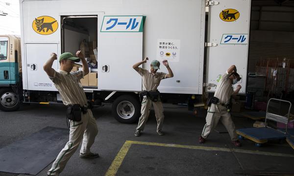 Länger arbeiten bei geringerem Verdienst. Lkw-Fahrer (hier Mitarbeiter der Yamato-Transport-Gruppe beim Dehnen vor Arbeitsbeginn) ist in Japan kein sonderlich beliebter Job.