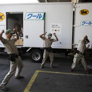 Länger arbeiten bei geringerem Verdienst. Lkw-Fahrer (hier Mitarbeiter der Yamato-Transport-Gruppe beim Dehnen vor Arbeitsbeginn) ist in Japan kein sonderlich beliebter Job.