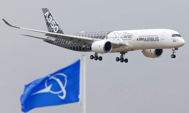 FILE PHOTO: An Airbus A350 jetliner flies over Boeing flags as it lands after a flying display during the 51st Paris Air Show at Le Bourget airport near Paris