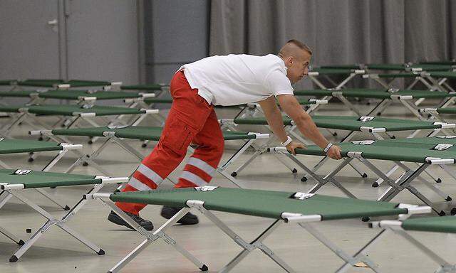 Symbolbild: Rotes-Kreuz-Mitarbeiter stellt Betten für Asylwerber bereit