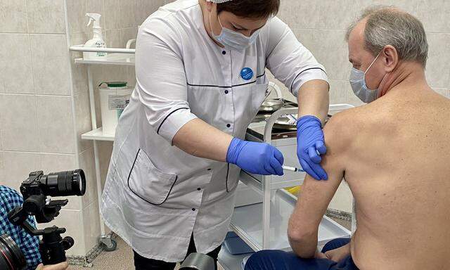 Das russische Vakzin „SputnikV“ wird einem 58-jährigen Patienten in der Moskauer Poliklinik 121 verabreicht. Das Medieninteresse zu Beginn der Impfkampagne ist groß. 